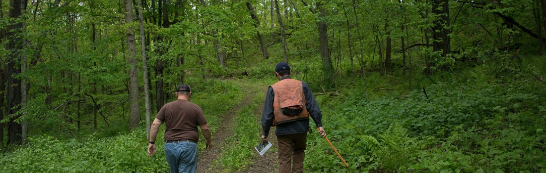 landowner and forester on a trail in the woods