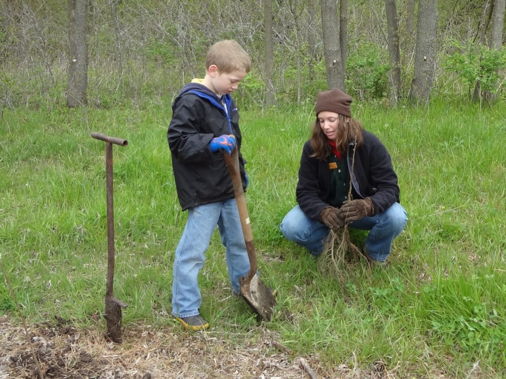 a child and a woman planting a tree seedling