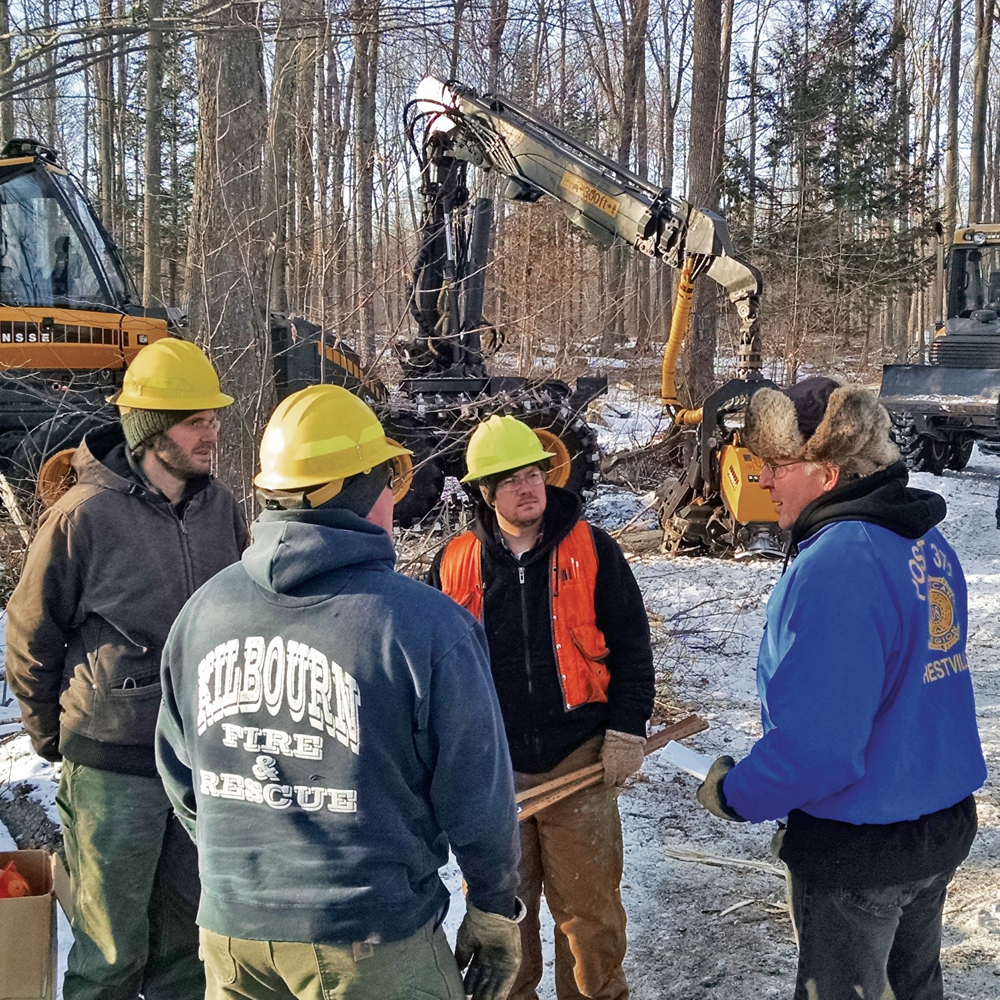 a group of people in hard hats with a back hoe in the background