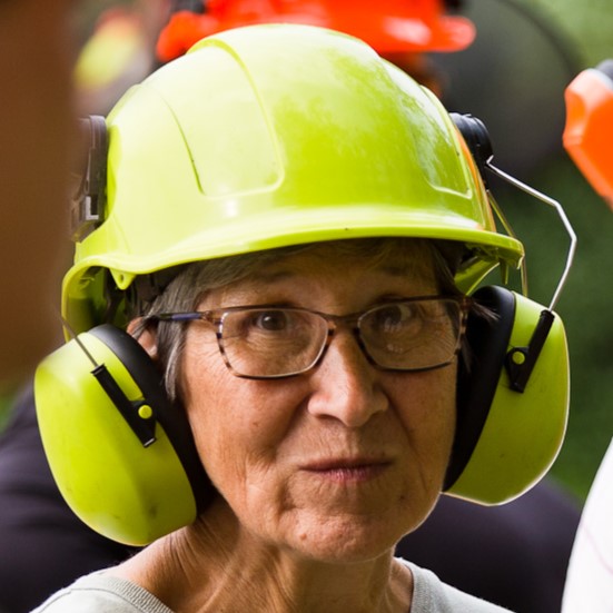 a women wearing a helmet and earmuffs to protect from the loud noises of chainsaws