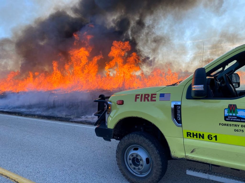 Wisconsin DNR truck next to wildfire flames