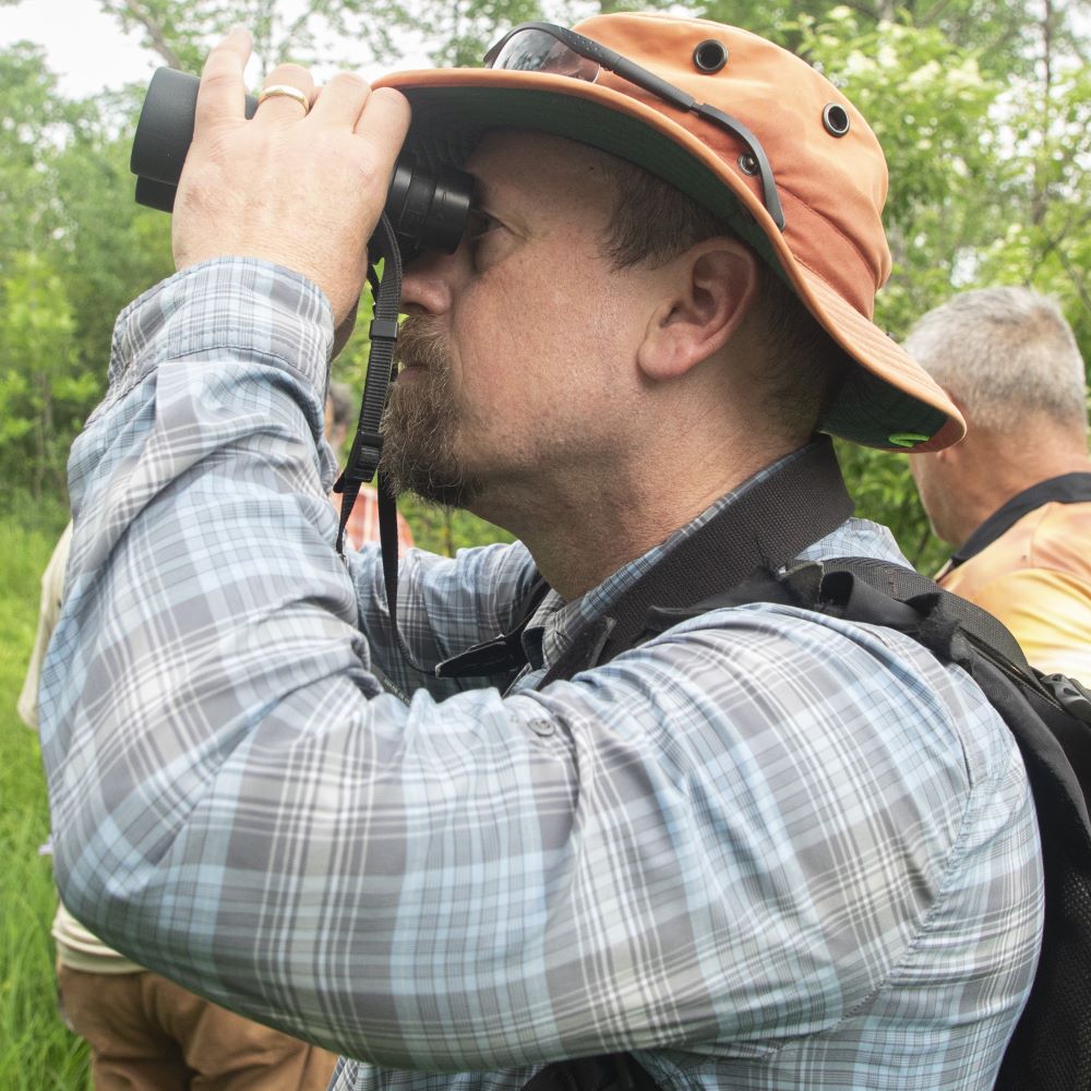 A man looking through birding binoculars