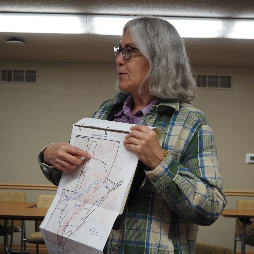 A woman pointing at a spot on a map of her woodland