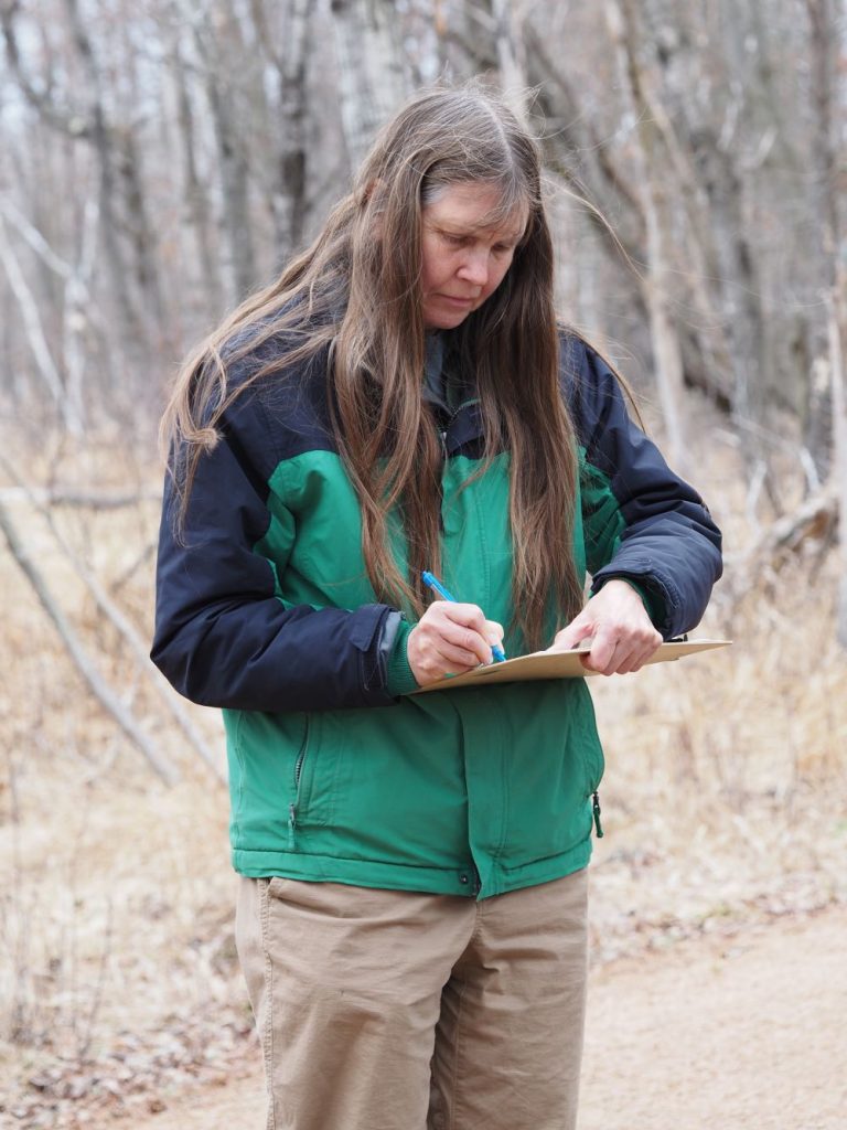 a woman standing outside writing on a clipboard
