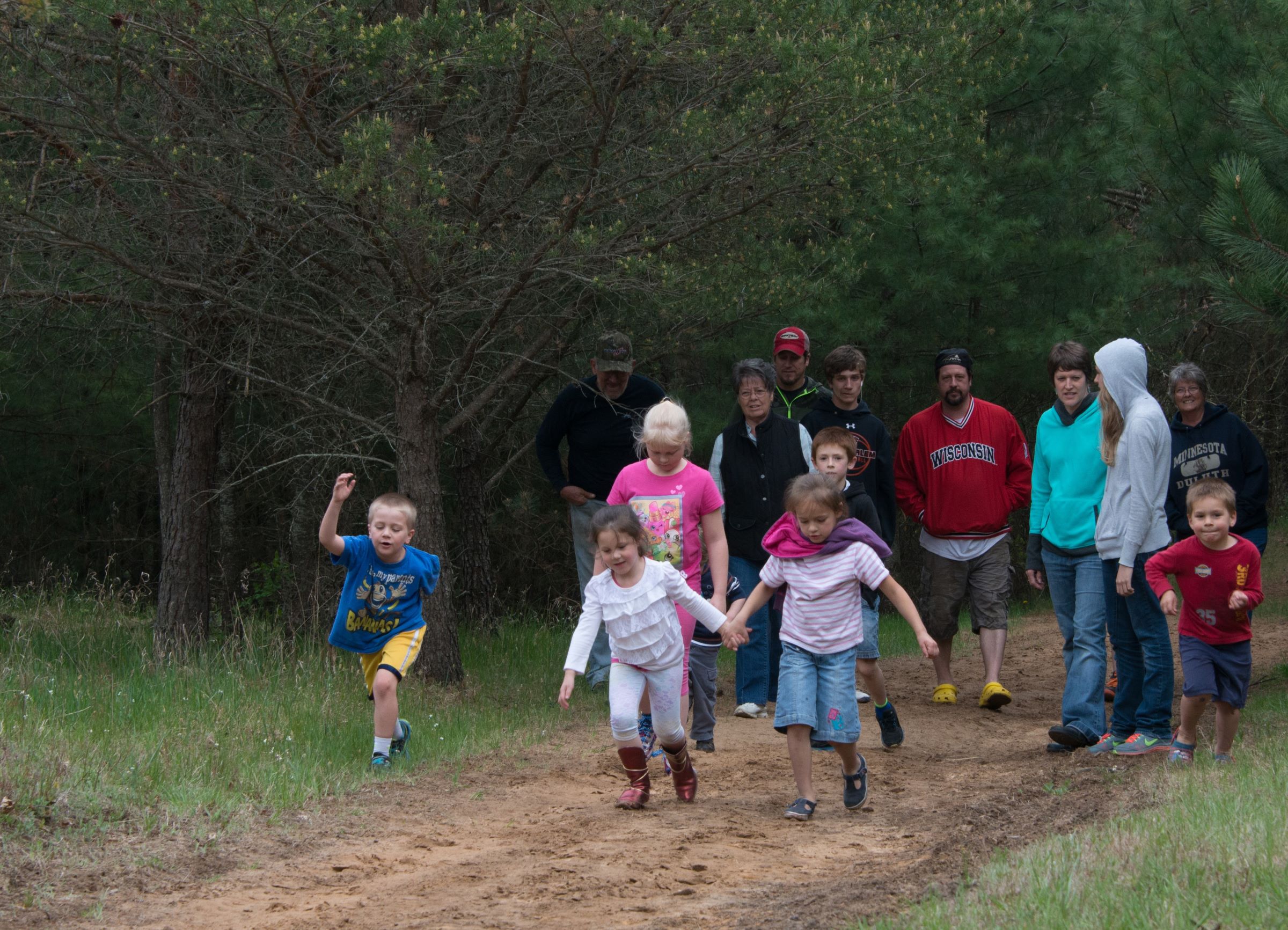 adults and kids walking on a forest trail