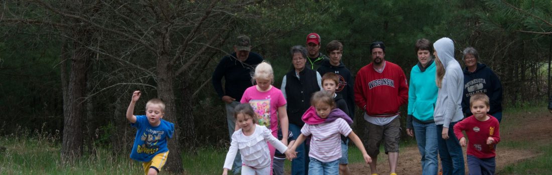 adults and kids walking on a forest trail