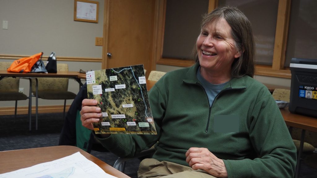 A woman smiling and holding a map of her woodland