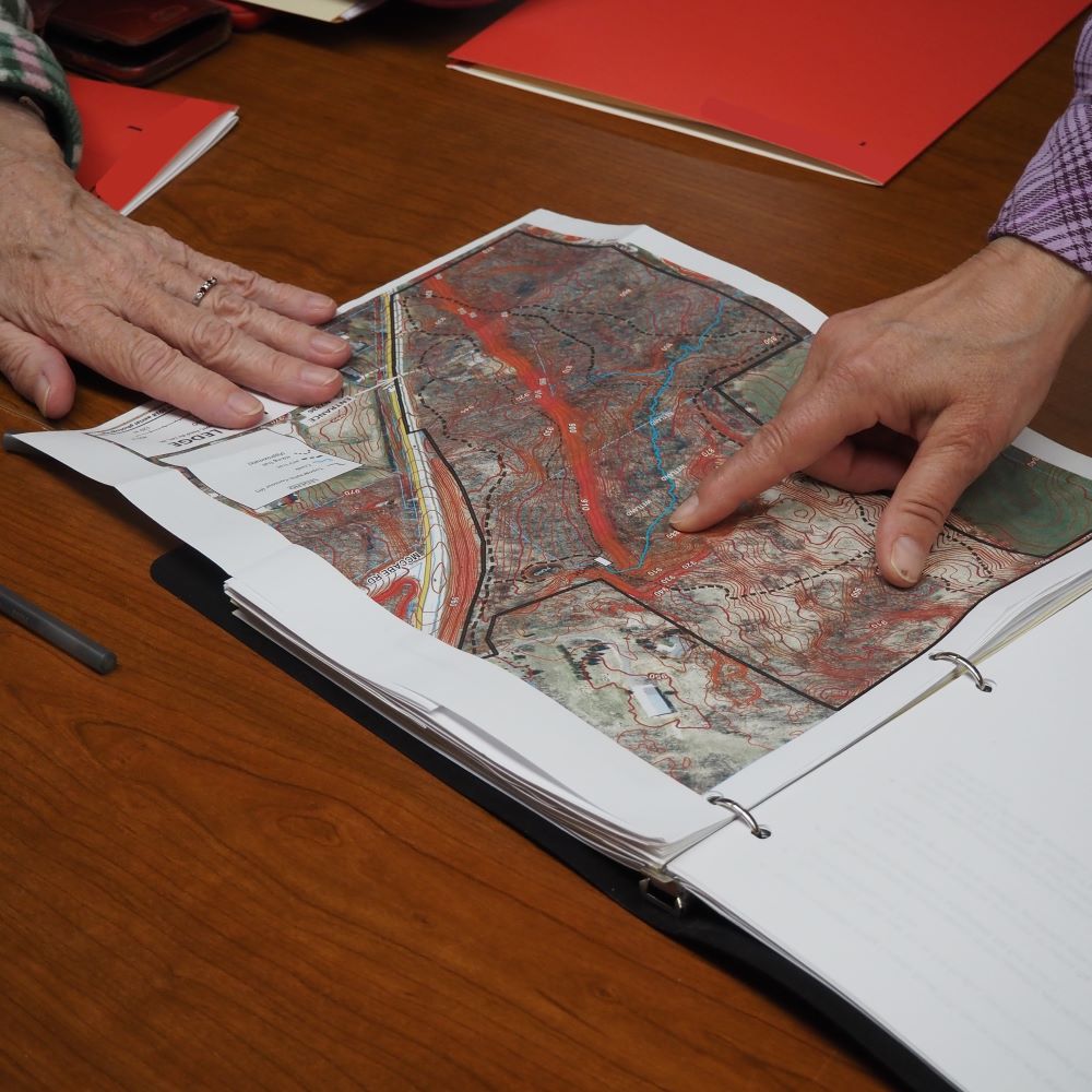 a hand pointing at a property map on a table